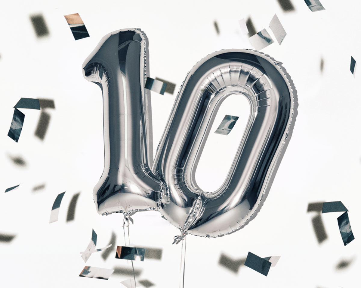 Stříbrné fóliové balónky ve tvaru čísla 10 se roztříštěným konfety.