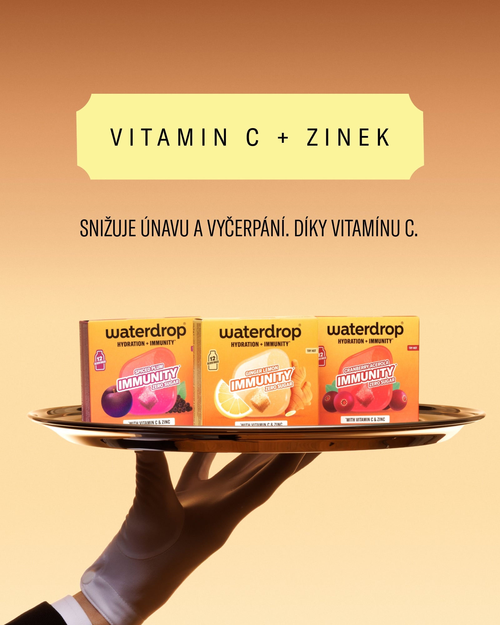 Tři krabičky Waterdrop vitamínu C na tácu, který drží ruka, před oranžovým pozadím.