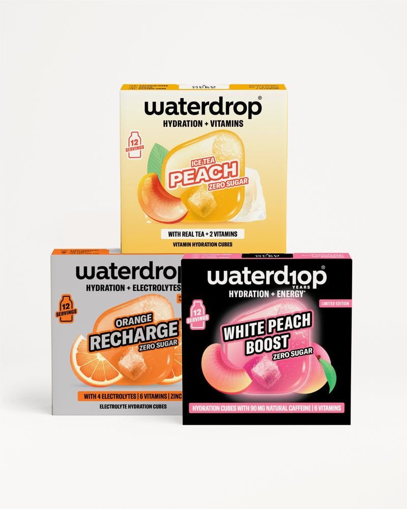 Tři krabičky Waterdrop pro hydrataci a vitamíny s příchutěmi broskev, Orange Recharge a White Peach Boost, naskládané na bílém pozadí.