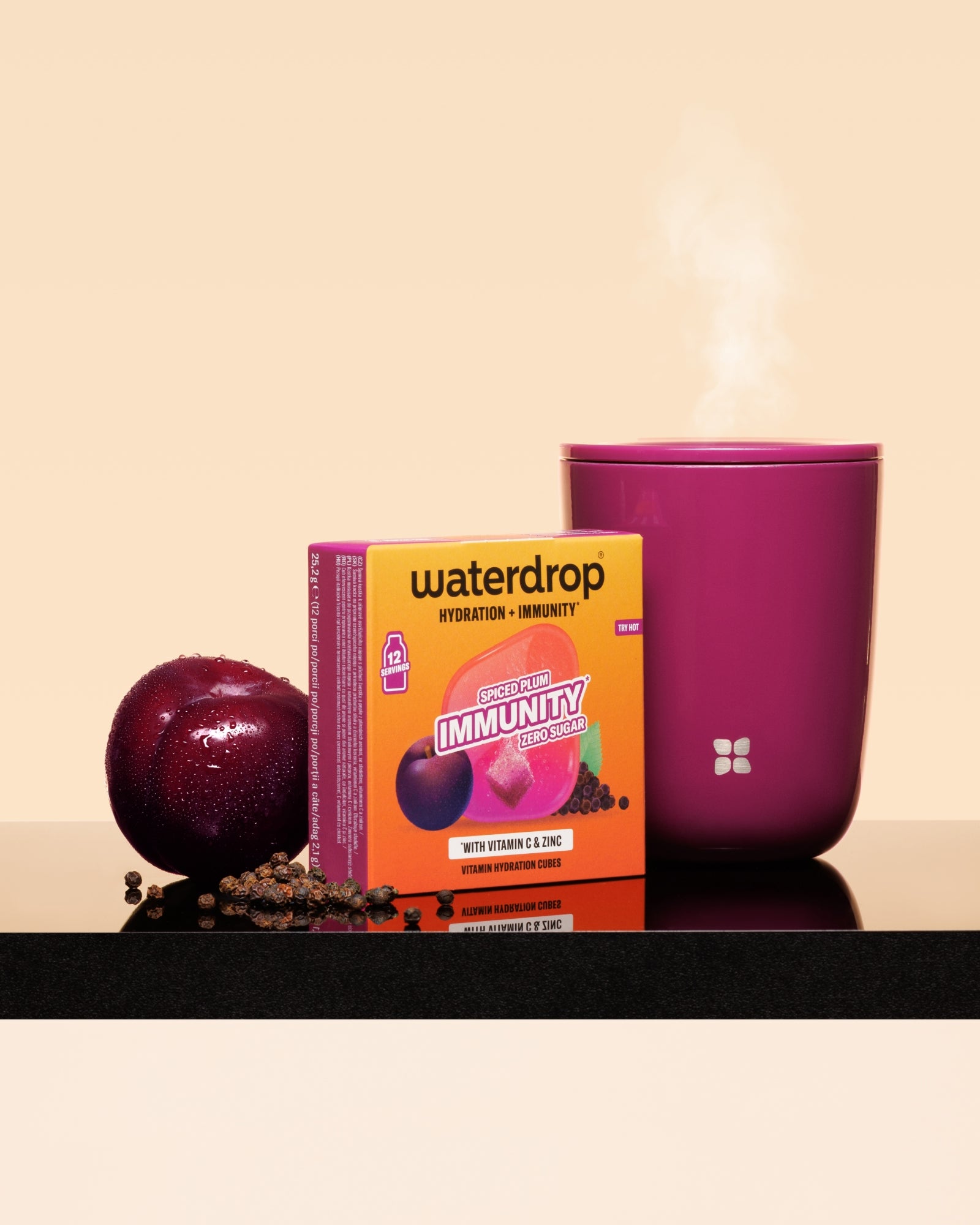 Krabička Waterdrop imunita boost vedle švestky a horké růžové šálky na černém povrchu.