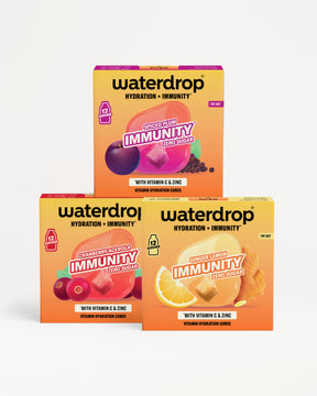 Tři krabice Waterdrop hydratace a imunity postavené do pyramidy s barevnými ovocnými motivy.